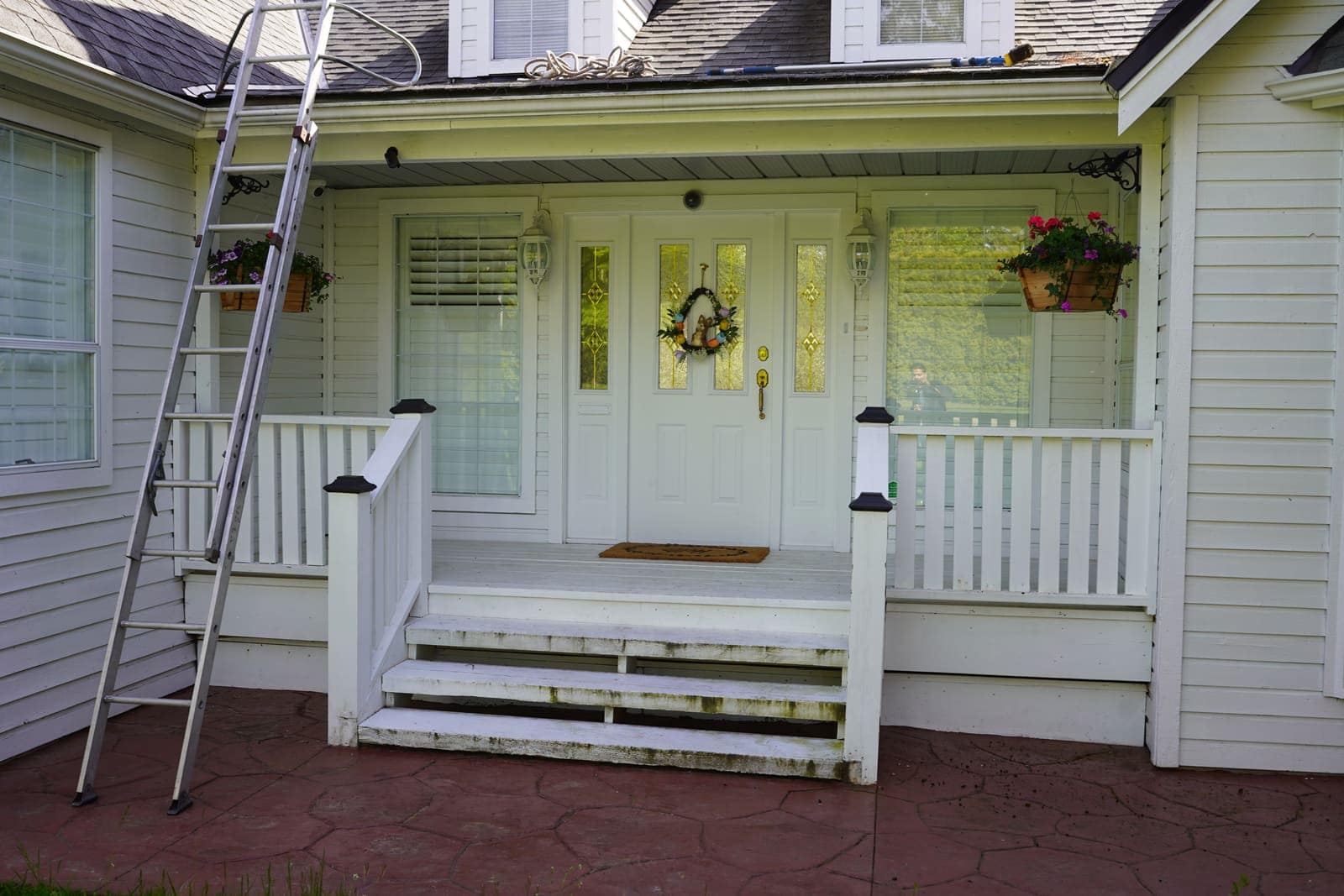 Ladder set at a covered porch ready for gutter cleaning