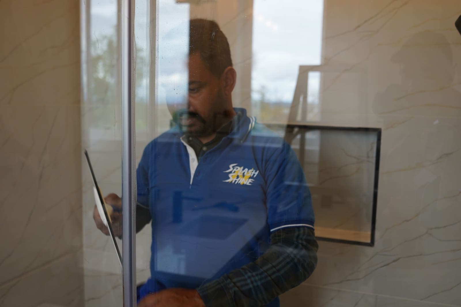 Window cleaner drawing a professional squeegee down a pane of glass, leaving a clean streak-free edge