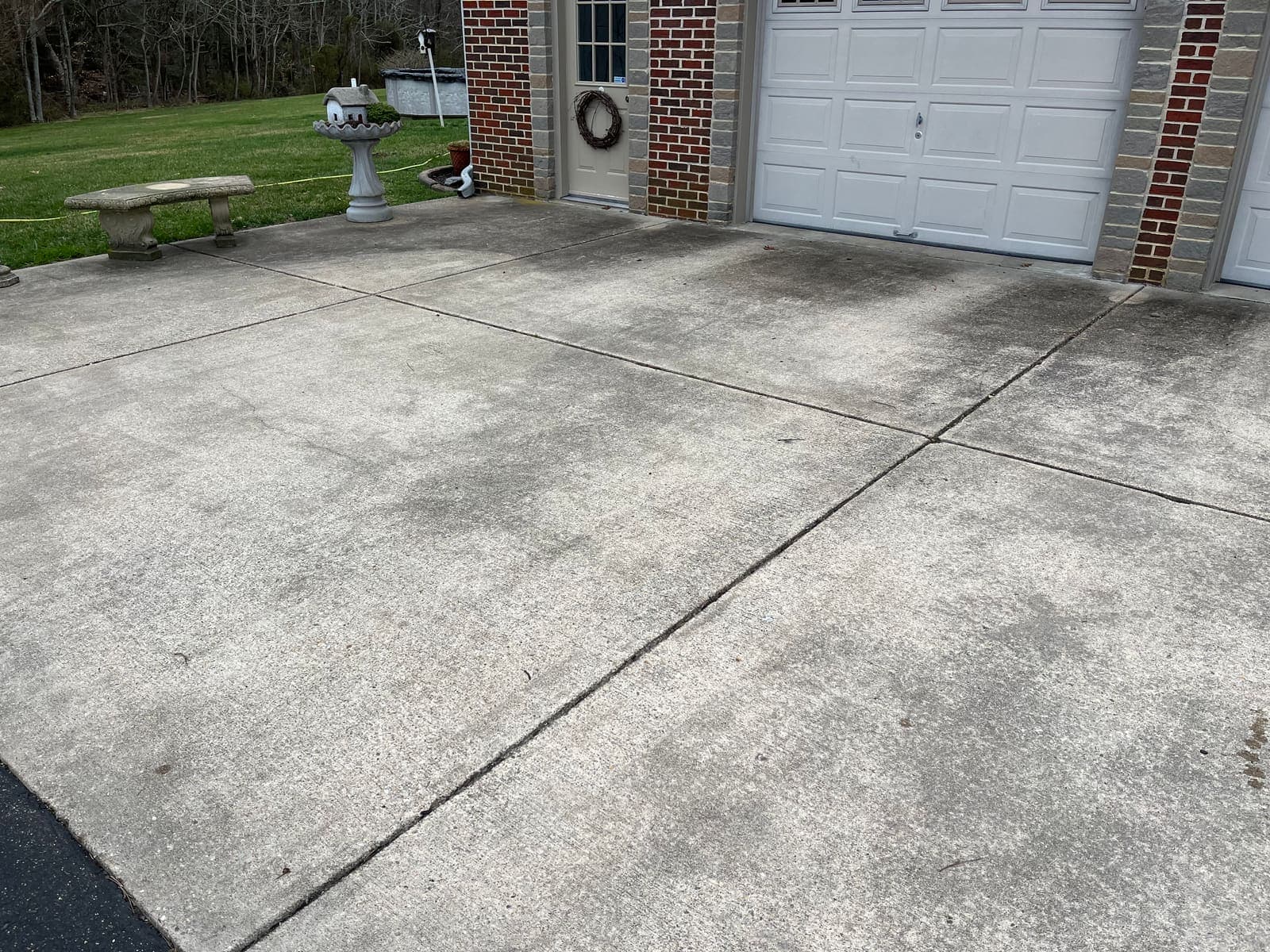 Concrete driveway in front of a garage before cleaning