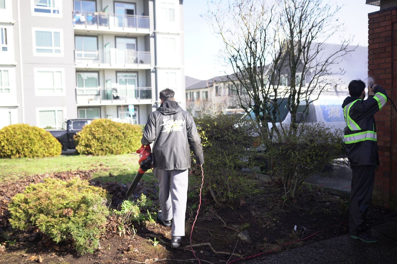 Worker pressure washing along a commercial landscaped edge