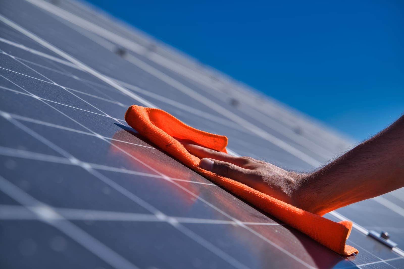 Hand squeegeeing water off a rooftop solar panel