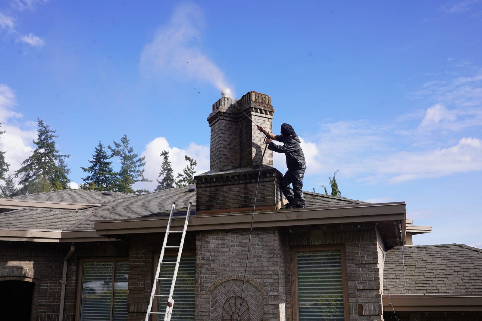 A worker cleaning a stone chimney on a roof