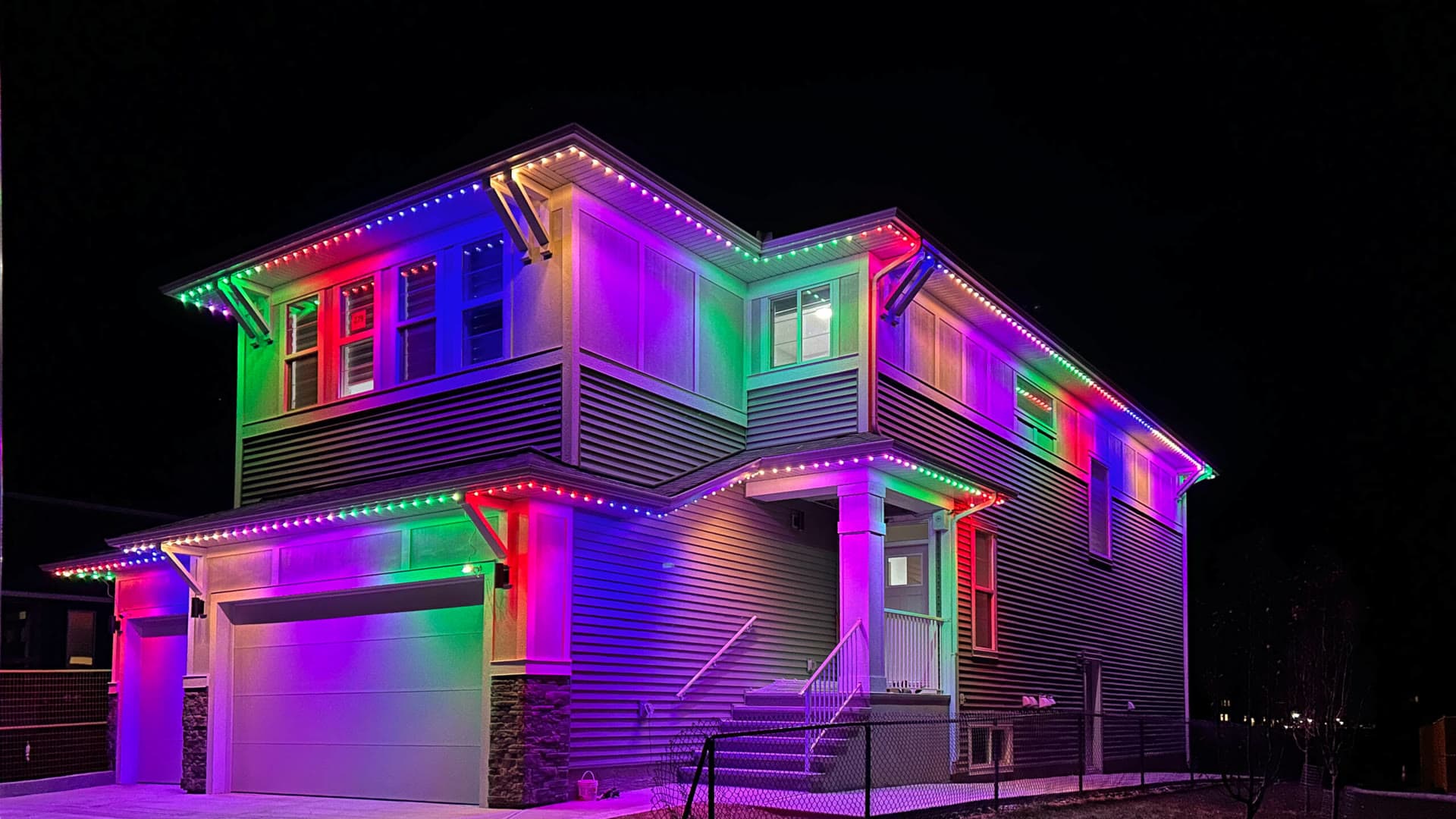 Two-storey Lower Mainland home glowing in full-colour permanent LED lights, purple, green, red and blue zones along every roofline