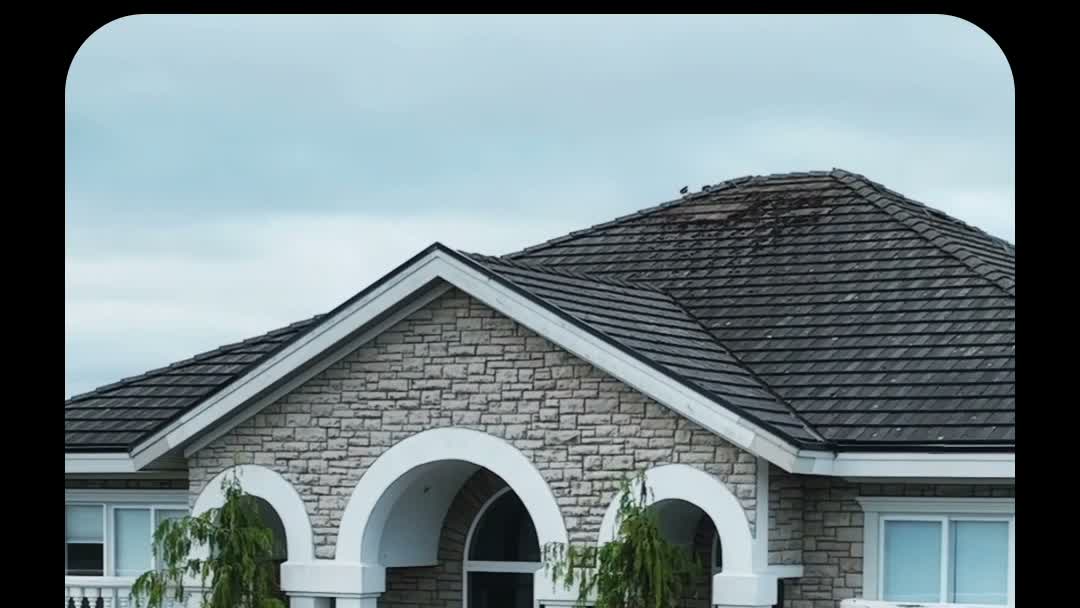 Grand farmhouse estate with arched entrance and concrete tile roof showing dark moss patches before cleaning