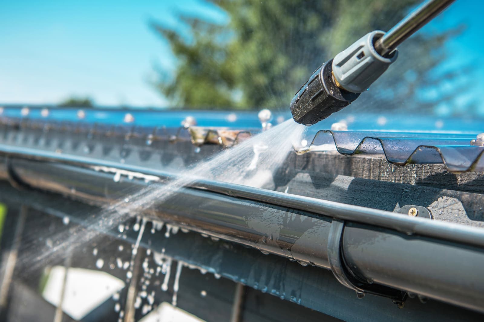 Gutter being flushed with water until it runs clear during a professional gutter cleaning