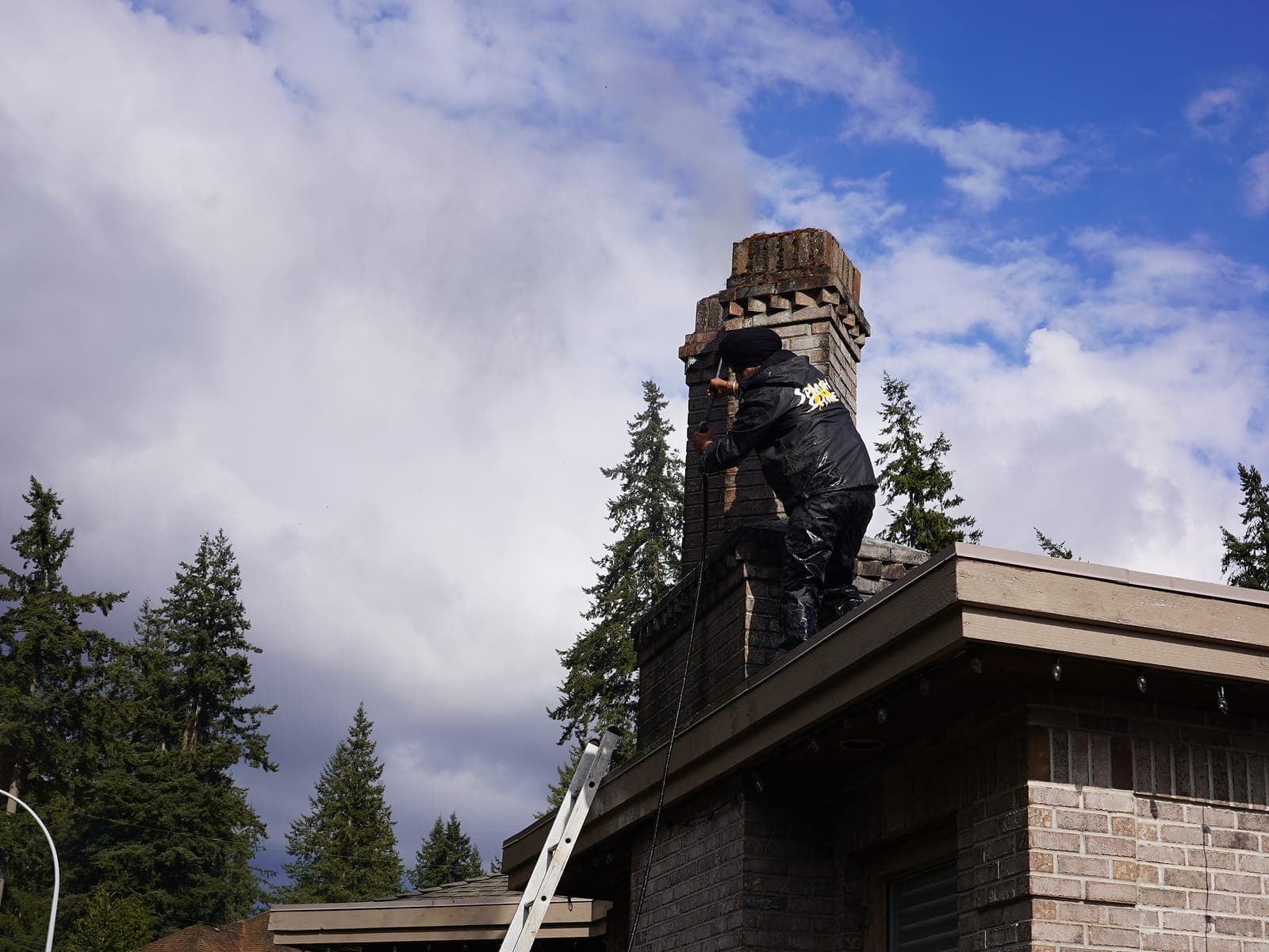Extension ladder set against a stone-fronted Lower Mainland home for safe roof access