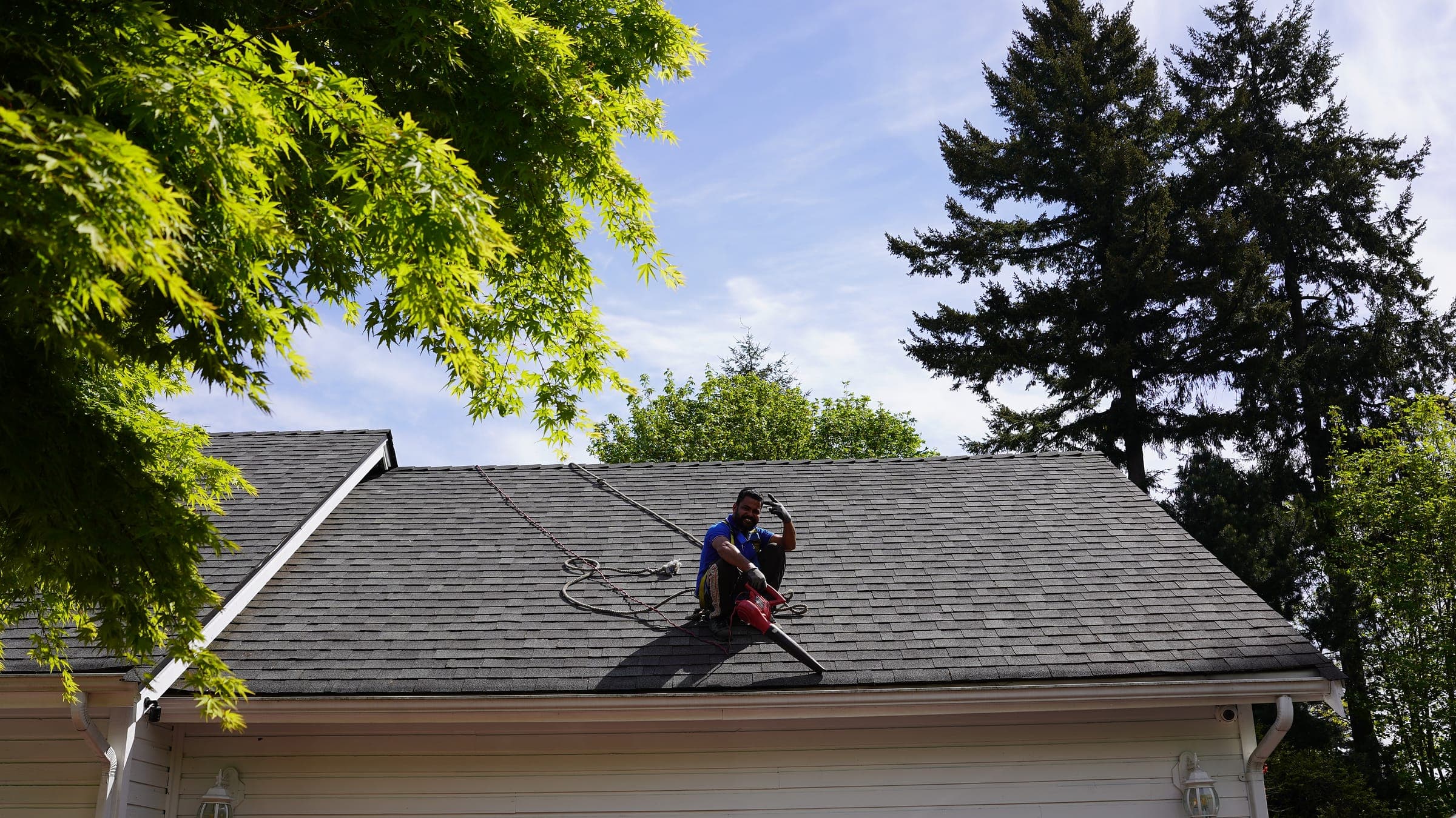 Splash N Shine technician harnessed on a residential asphalt shingle roof during a soft-wash roof cleaning in the Lower Mainland