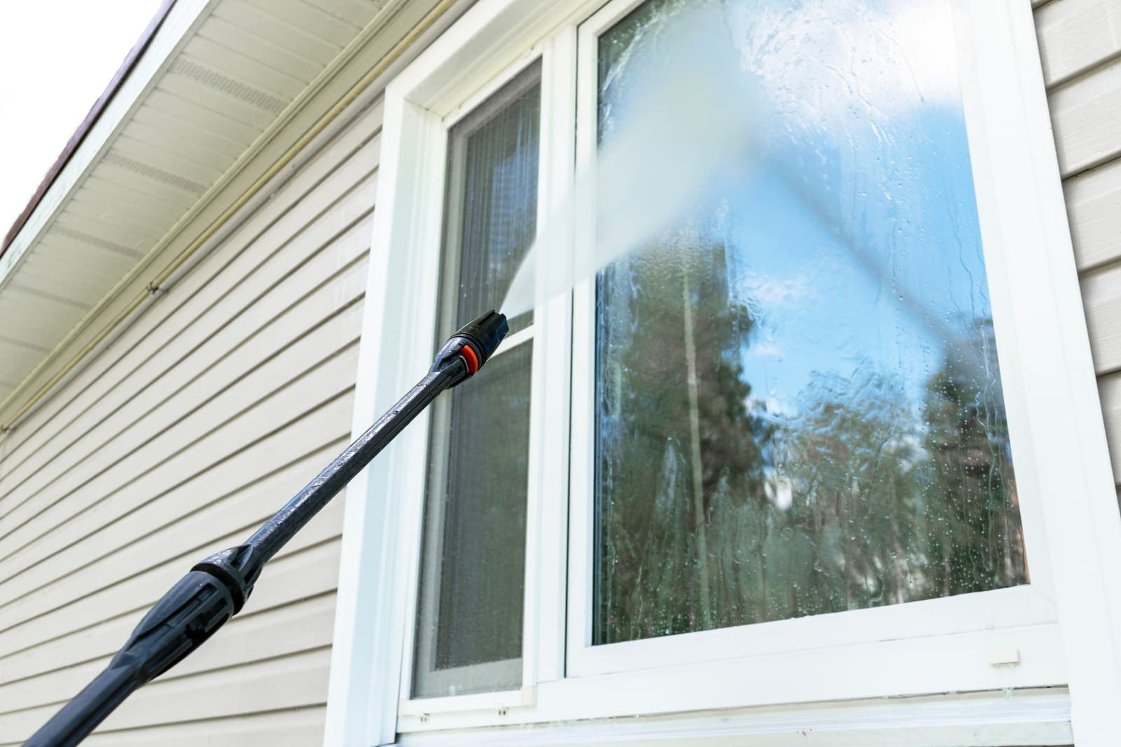 Exterior window being rinsed spot-free with a water-fed cleaning wand — Window Washing in Burnaby, BC