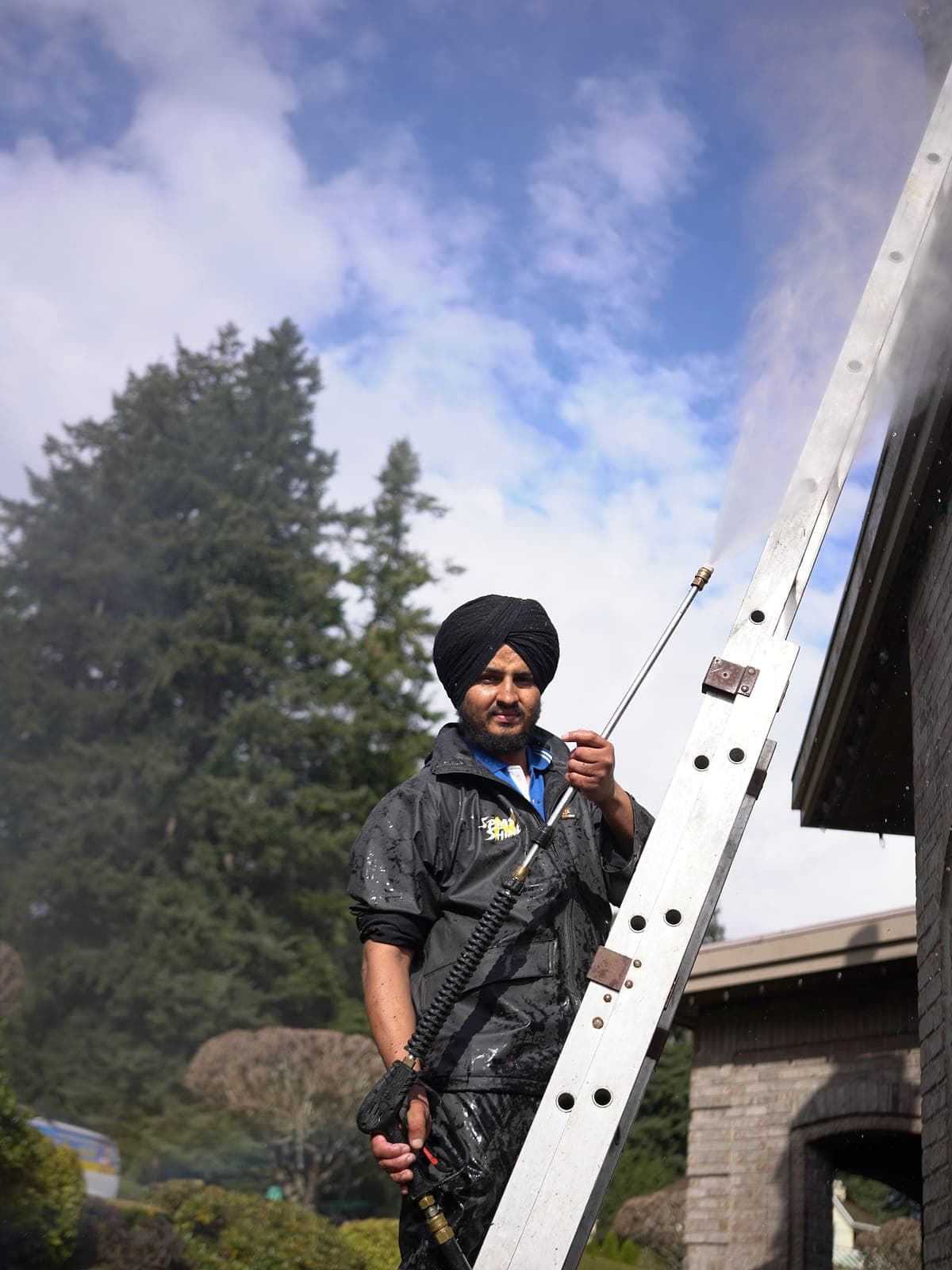 Splash N Shine technician carrying an extension ladder to a job at a Lower Mainland home
